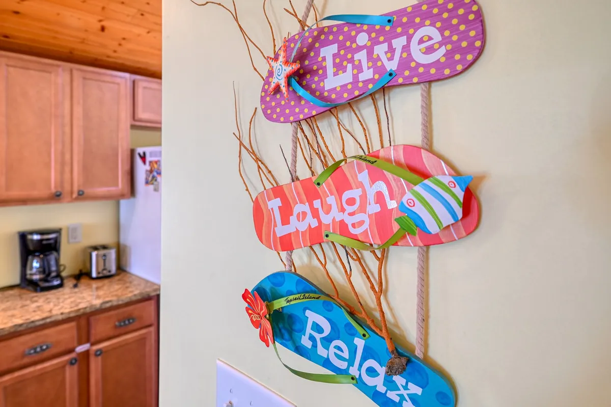 This cheerful kitchen scene features beach-themed decorative flip-flops, bright kitchen cabinets, and a convenient coffee maker, creating a lively and functional space for meal preparation and socializing.