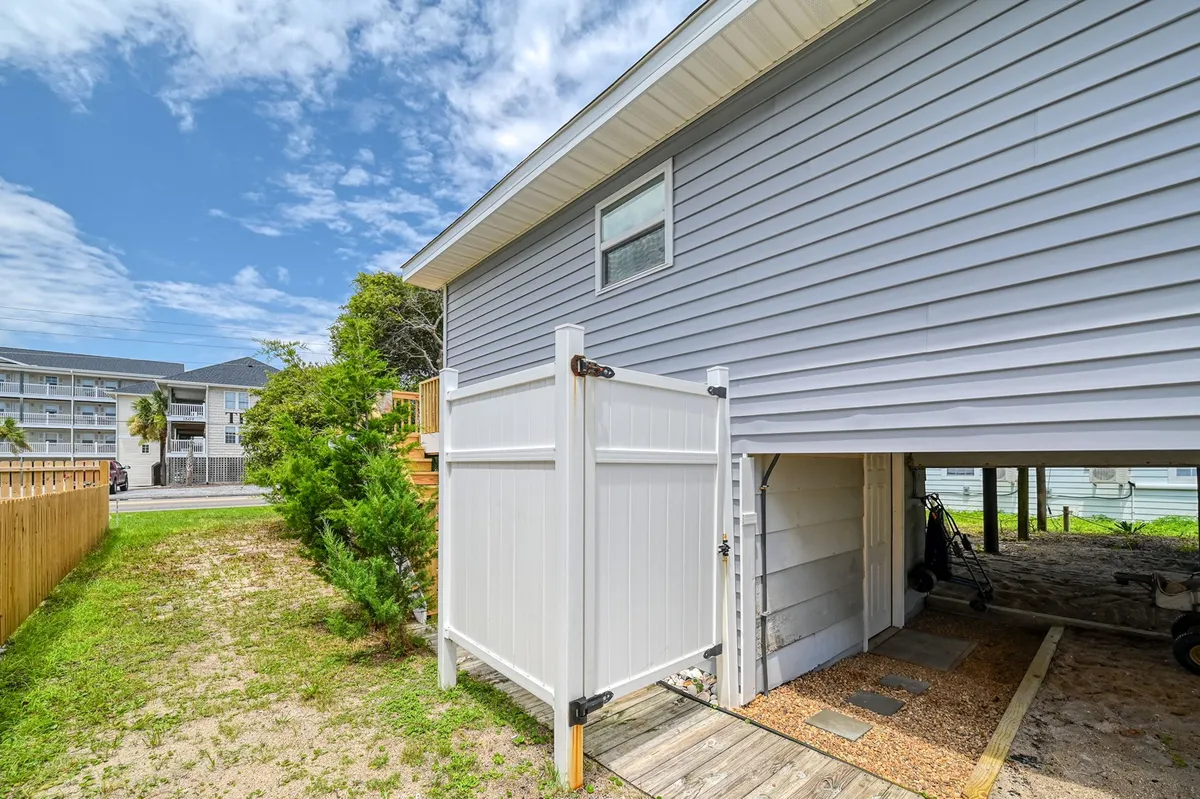 A welcoming exterior view featuring a gate entrance framed by lush landscaping and the house’s exterior wall. The scene suggests a peaceful, pet-friendly neighborhood, perfect for walks with your dog and easy access to outdoor adventures.